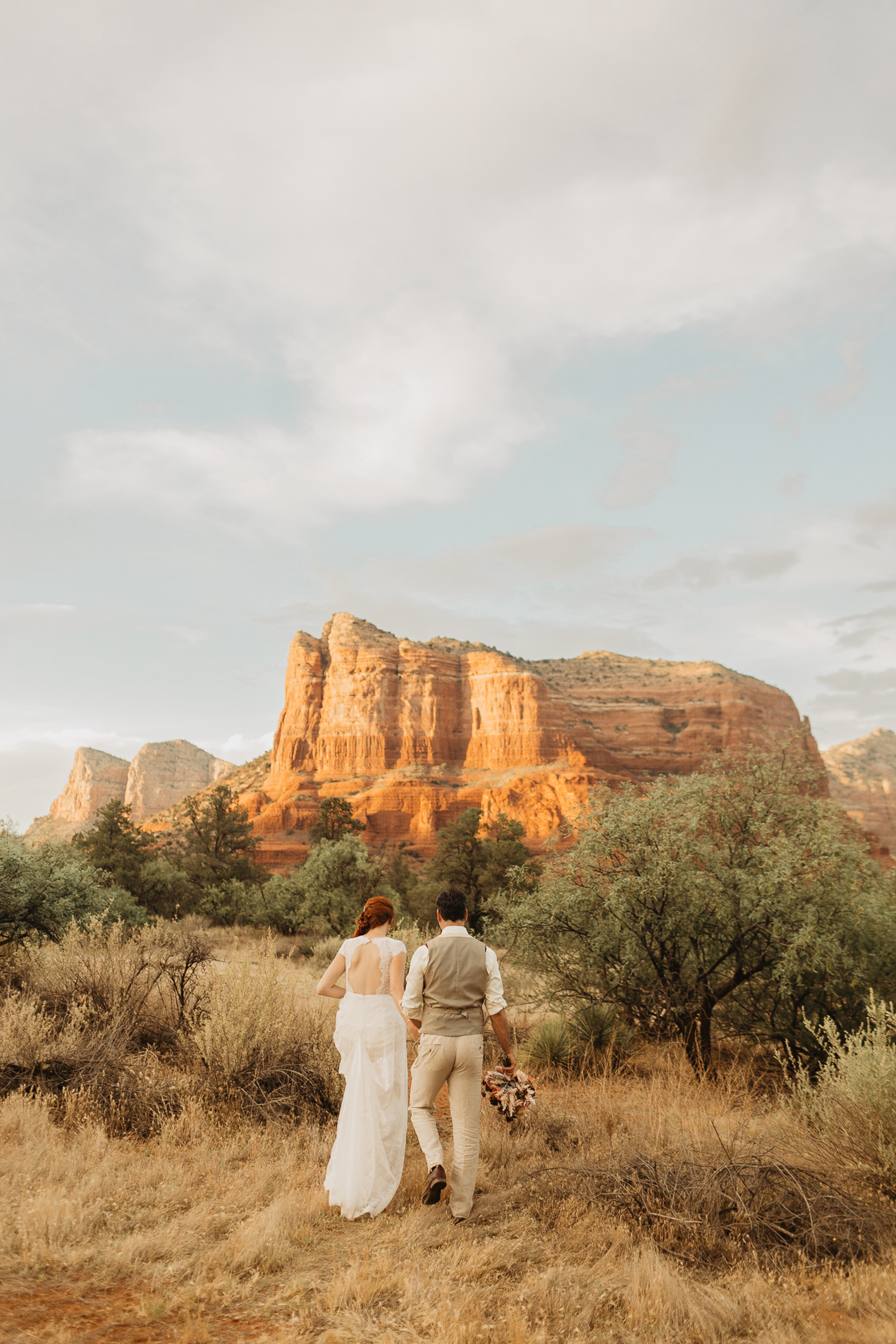 Bride and groom walking towards the Sedona red rock mountains