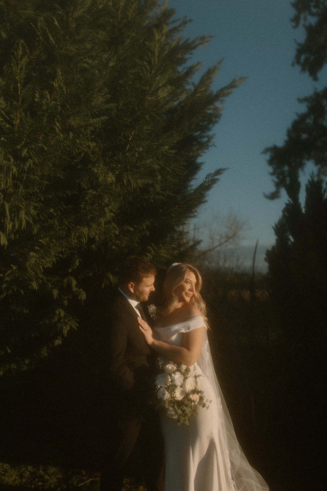 film inspired wedding portrait of a bride and groom standing between trees on a winter day in Oregon